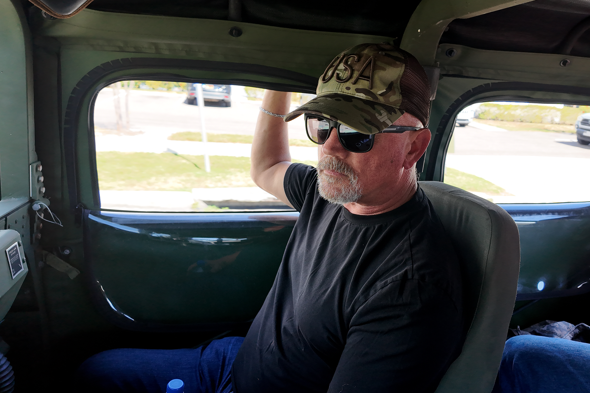 man wearing a USA hat in a vintage army jeep